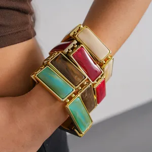 Close-up of a chunky colorful resin rectangular stretch bracelet with gold-toned frames.