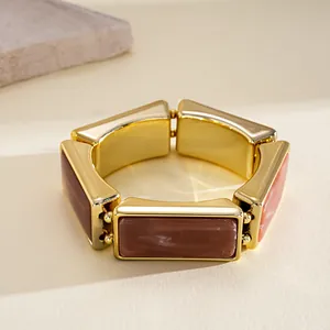 Detail view of a vintage rectangular resin segmented elastic bracelet with gold trim.