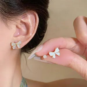 Close-up of elegant 14K gold-plated butterfly earrings with zircons and white enamel