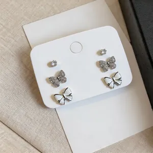 Detail view of 3-pair earring set with zircon butterflies and white enamel bows