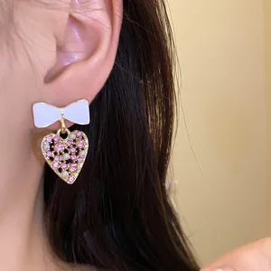 Detailansicht von Schleifen-Herz-Ohrringen mit rosa Strasssteinen und weißen Perlen