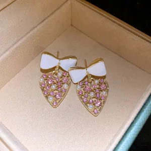 Detaillierte Ansicht eleganter Herzohrringe mit Schleife, rosa Strasssteinen und Perlen.
