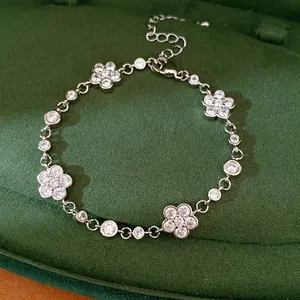 Close-up of elegant silver bracelet with flower and round zircon charms on green velvet.