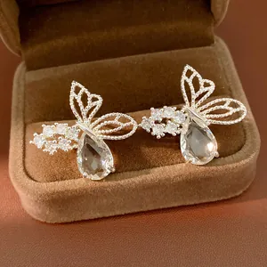 Macro shot of silver earrings featuring zircon-encrusted butterfly and drop-shaped stones