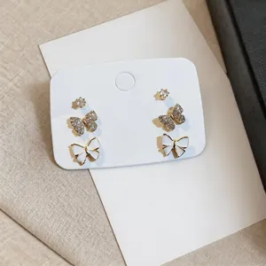 Detailed view of 3 pairs of gold-plated butterfly and zircon stud earrings on card.