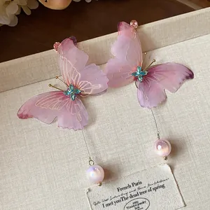 Detailed view of pink chiffon butterfly earrings with blue crystals and dangling pearls