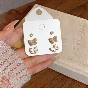 Detailed view of 14K gold plated zircon and white enamel butterfly stud earring set on card