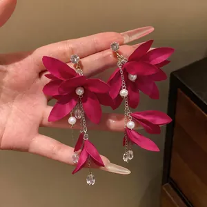 Detail view of deep rose red fabric flower earrings with long pearl tassels and zirconia