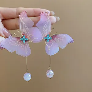 Detailed close-up showing texture of pink chiffon butterfly earrings with blue crystals