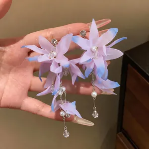 Detailed macro view of elegant purple fabric flower tassel earrings with pearls and zircons