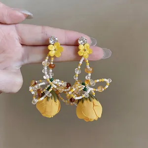 Handmade yellow fabric flower drop earrings with intricate beaded tassel design for vacation