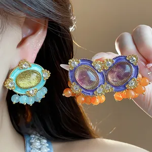 Detailed close-up of vintage resin oval stud earrings with rhinestones and beads.