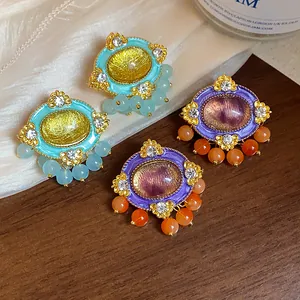 Close-up detail of vintage-style oval resin earrings with colorful enamel and beads.