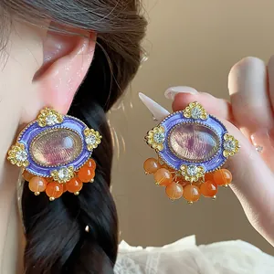 Detailed view of vintage purple oval stud earrings with crystals and orange resin beads