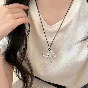 Close-up of minimalist silver beaded flower pendant necklace on model wearing white shirt