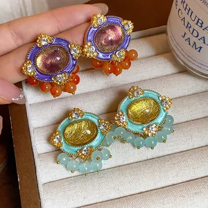 Close-up of vintage resin earrings with rhinestones and beaded fringe details