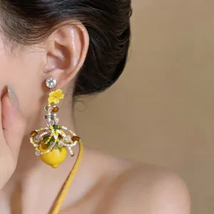 Macro detail of a vacation style handmade lemon and yellow flower tassel earring