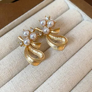 Detailed macro view of elegant gold-finished bow earrings adorned with pearls and crystals.