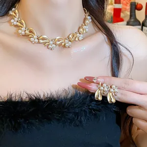 Elegant gold bow pearl necklace and earring set shown on a model for a luxury look.