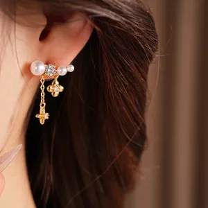 Orecchini dorati con perle, zircone, fiore e nappe a stella sull'orecchio della modella.