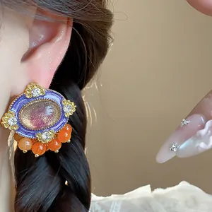 Close-up of vintage resin oval stud earrings with crystals and orange bead drops