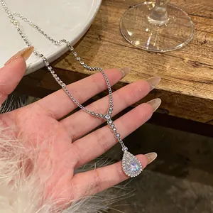 Close-up of minimalist teardrop zircon necklace on hand with refined detail.