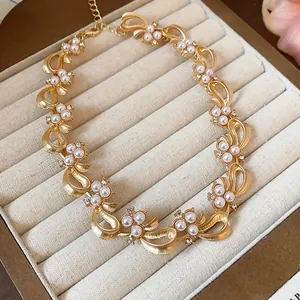 Elegant gold-tone bow necklace with white pearls and crystals displayed in a velvet box