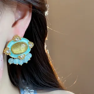 Close-up detail of vintage style oval resin stud earring with rhinestones worn on ear
