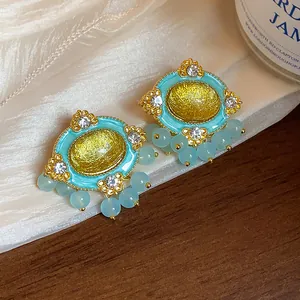Close-up detail of vintage gold oval resin earrings with blue beads and rhinestones