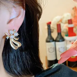 Detailed view of elegant gold bow stud earrings with pearls and crystals worn on a model's ear