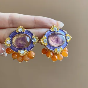 Close-up detail of vintage-style oval stud earrings with purple enamel and orange beads