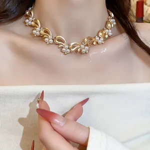 Close-up detail of a vintage-style gold-tone ribbon necklace with inlaid pearls.