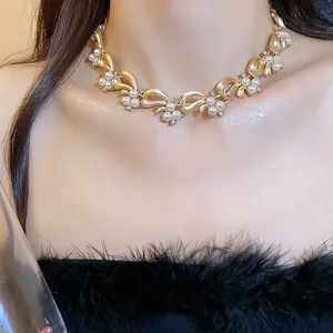 Detailed close-up of a luxury golden bow-shaped ribbon necklace with delicate pearls.