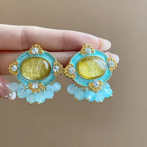 Close-up of vintage resin oval stud earrings with turquoise borders and blue beads