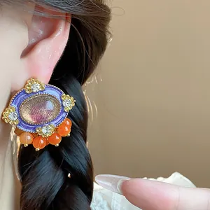 Detailed view of vintage-style resin oval earring with rhinestones and orange beads