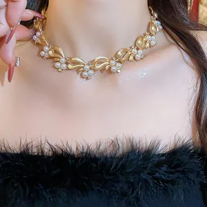Close-up of an elegant gold-toned bow-knot pearl necklace worn on neck with luxury feel.
