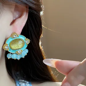 Vintage oval resin earrings with shiny rhinestones and light blue beads shown on ear