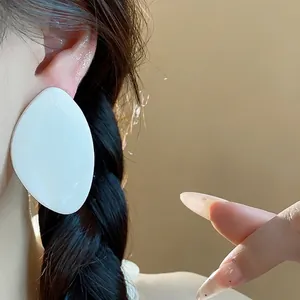 Boucles d'oreilles géométriques minimalistes en résine blanche sur un mannequin chic