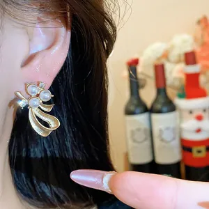 Close-up of an elegant golden bow-knot stud earring with pearls and clear crystals.
