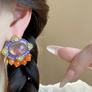 Detail of vintage resin oval stud earring with purple enamel and orange beads on ear