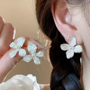 Dettaglio di eleganti orecchini a lobo a forma di fiore bianco con perle centrali