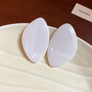 Boucles d'oreilles géométriques en résine blanc crème en forme de pétale sur une assiette