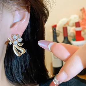 Detailed macro view of an elegant golden bow stud earring with pearls and crystals.