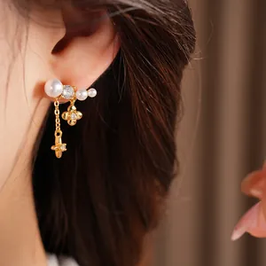Primo piano di orecchini placcati oro con nappe, perle, fiore di zircone e pendente a stella.