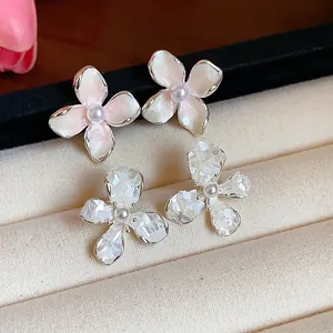 Dettaglio macro di delicati orecchini a lobo a fiore con perle e petali rosa e bianchi