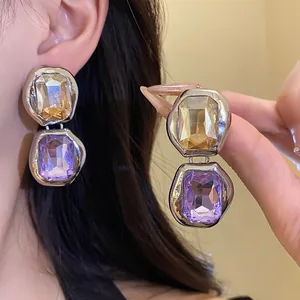 Close-up of bicolor square crystal pendant earrings featuring silver-toned frames