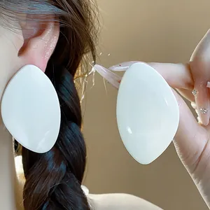 Vue détaillée de grandes boucles d'oreilles géométriques en résine blanche minimalistes