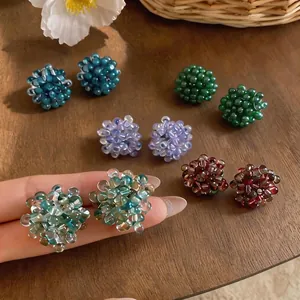 Colorful glass beaded flower stud earrings in multiple colors on a wooden background