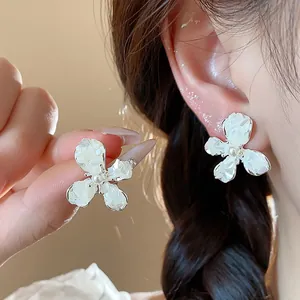 Dettaglio ravvicinato di eleganti orecchini a lobo con fiori bianchi e perle dal design raffinato