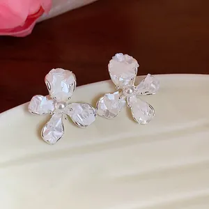 Macro dettaglio di eleganti orecchini a lobo a fiore in argento con madreperla e perla